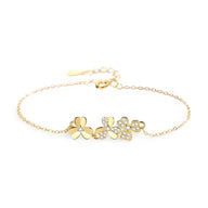 Bracelet en or avec pendentifs trèfle à trois feuilles, chaîne fine et fermoir ajustable.