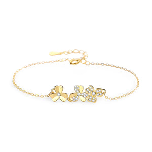 Bracelet en or avec pendentifs trèfle à trois feuilles, chaîne fine et fermoir ajustable.