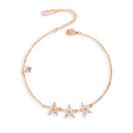 Bracelet fin en or rosé avec trois étoiles délicates serties de pierres brillantes.