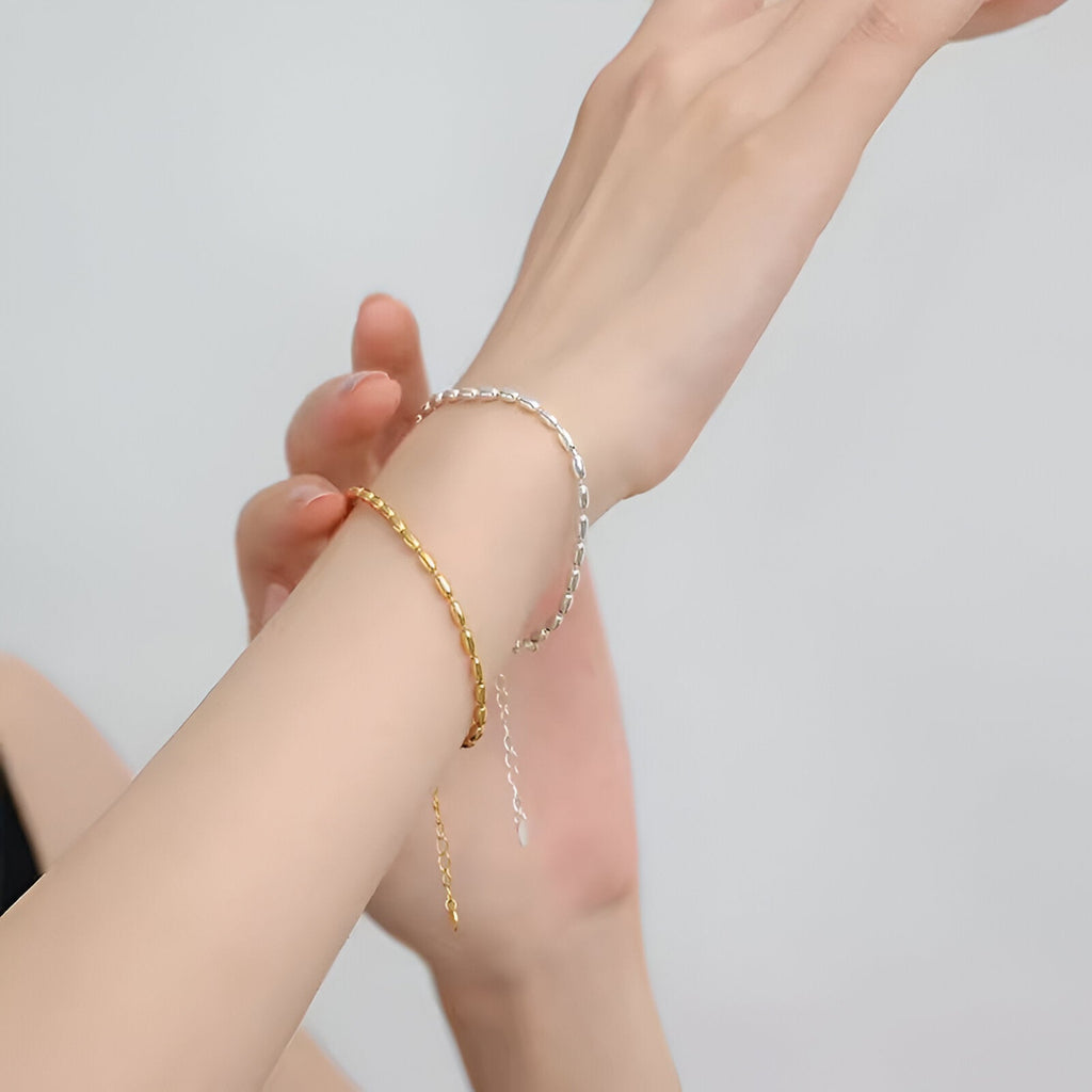 Bracelet fin grain de riz en argent sterling porté au poignet, style délicat et élégant.