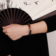 Bracelet mixte en bois de palissandre marron et perles d'ébène noir sur poignet.