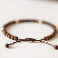 Bracelet ajustable en perles de bois de santal marron avec cordon tressé élégant pour femme.