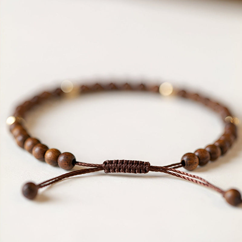 Bracelet ajustable en perles de bois de santal marron avec cordon tressé élégant pour femme.
