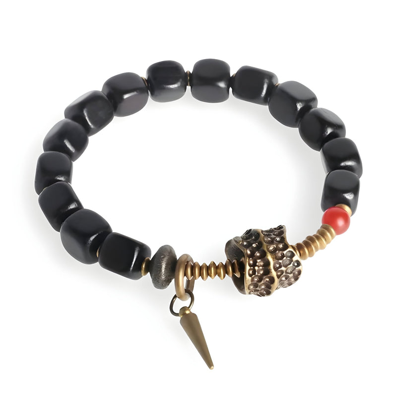 Bracelet femme en bois d'ébène noir avec détail en métal antique et perle rouge.