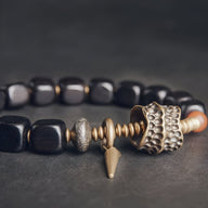 Bracelet femme en bois d'ébène noir avec détails antiques en métal doré et perle texturée.