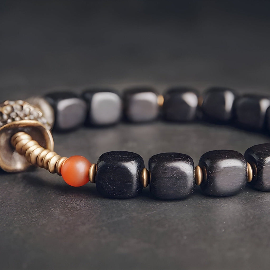 Bracelet femme en bois d’ébène noir avec perles rondes et détail antique en métal cuivreux.