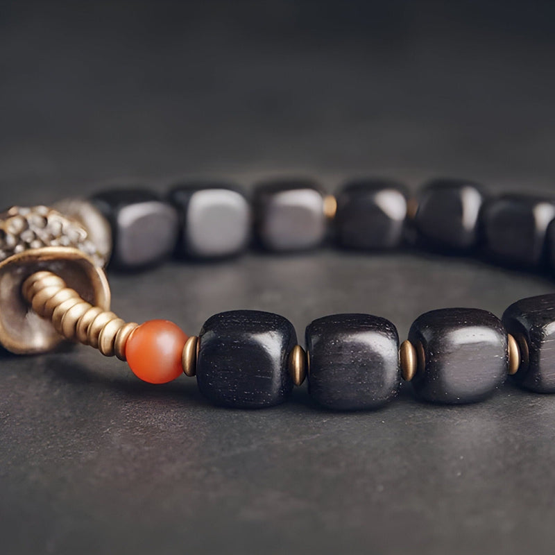 Bracelet femme en bois d’ébène noir avec perles rondes et détail antique en métal cuivreux.