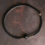 Bracelet femme en perles noires d’ébène et détails en cuivre avec nœud ajustable.