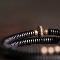 Bracelet adaptatif en ébène noir avec perles en cuivre brossé et centrale texturée.