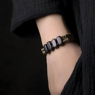 Bracelet femme flexible en bois d’ébène noir avec éléments en cuivre sur poignet.