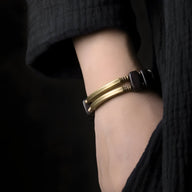 Bracelet flexible en bois d'ébène noir avec détails en cuivre, porté au poignet féminin.