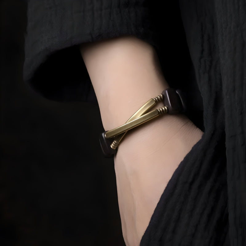 Bracelet flexible en bois d'ébène noir et cuivre avec design torsadé sur poignet féminin.