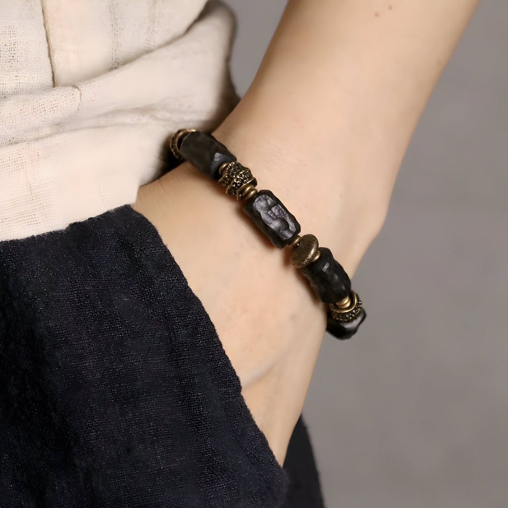 Bracelet mixte en bois d'ébène noir et laiton avec détails sculptés, style unique et artisanal.