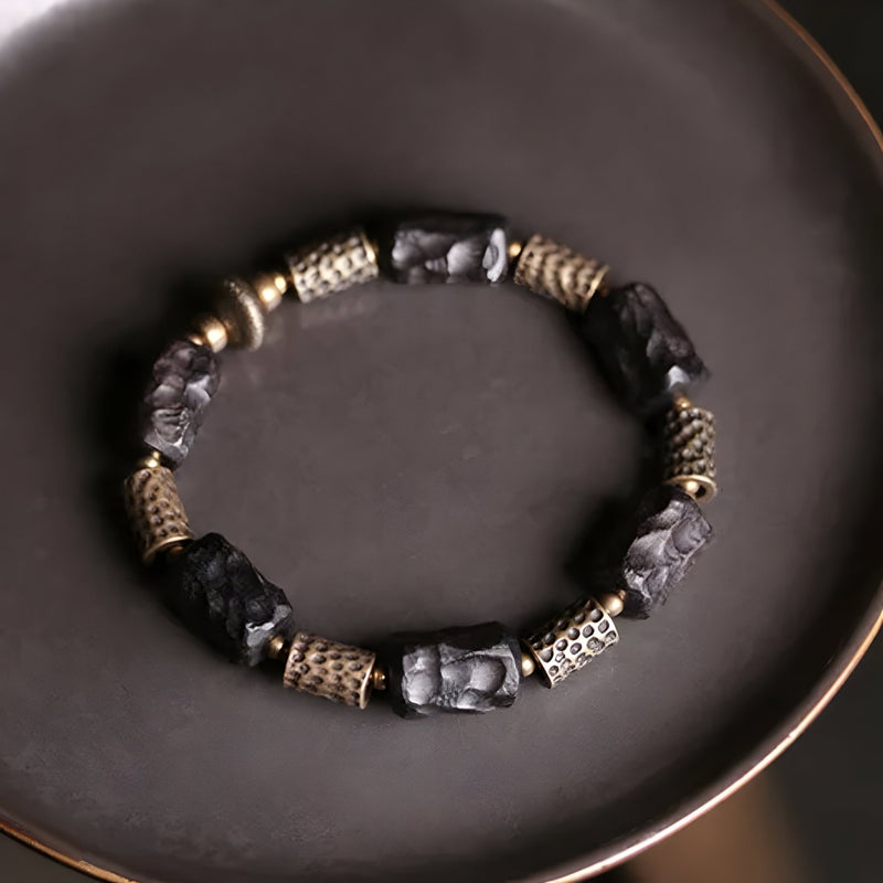 Bracelet mixte en bois d’ébène noir sculpté et éléments en laiton doré sur fil élastique.