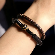 Bracelet mixte en bois d'ébène noir et perles d'obsidienne avec détail doré, style naturel.