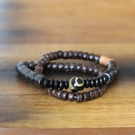 Bracelet mixte en bois d'ébène noir et perles d'obsidienne avec perle centrale beige à motif noir.
