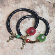 Bracelet en bois d'ébène noir avec perles en verre rouge et vert, détails en métal doré, style subtil et élégant pour femme.