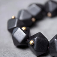 Bracelet femme en bois d’ébène noir mat avec perles dorées, style géométrique moderne.