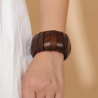 Bracelet large en bois naturel de teinte café avec segments lisses, porté au poignet féminin.