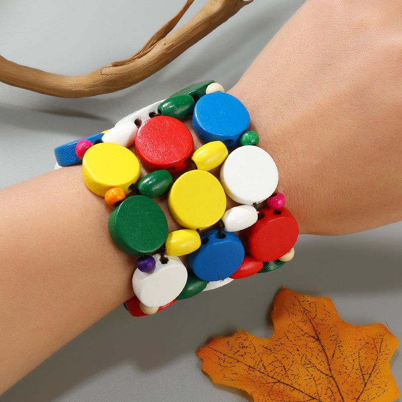 Bracelet large femme en bois naturel multicolore avec perles rondes plates et petites billes colorées.