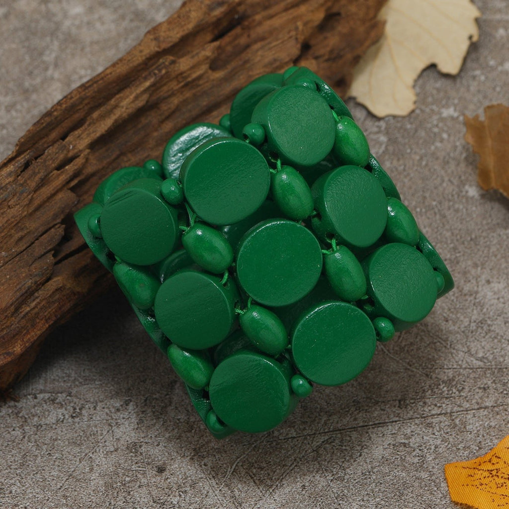 Bracelet large en bois naturel peint vert, composé de pastilles rondes assemblées et cousues.