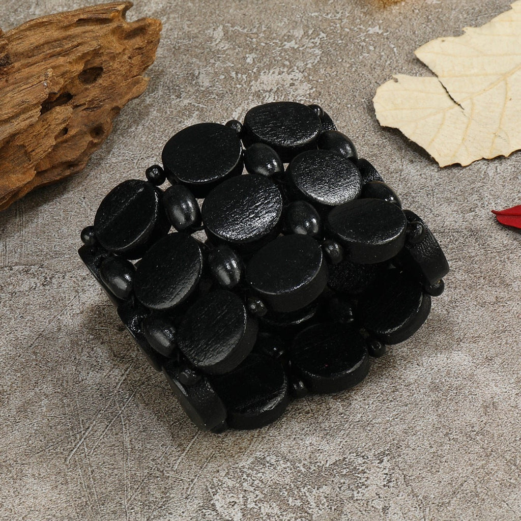 Bracelet large en bois naturel noir avec perles ovales lisses et texture mate.