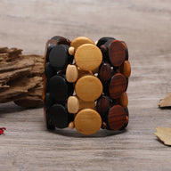 Bracelet large en bois naturel avec gros ronds marron clair, noir et foncé entrelacés.