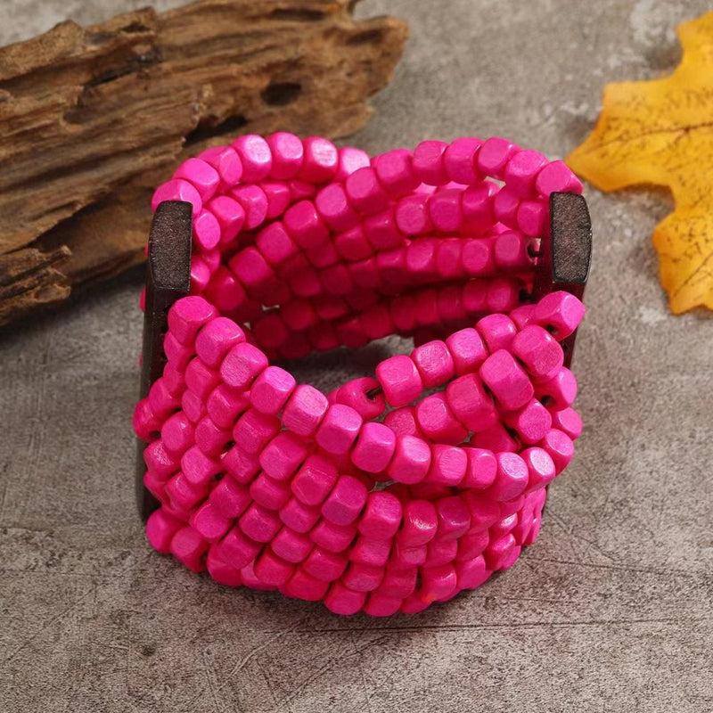 Bracelet touffeté en bois naturel teinté rose vif, style ample et texturé pour femme.