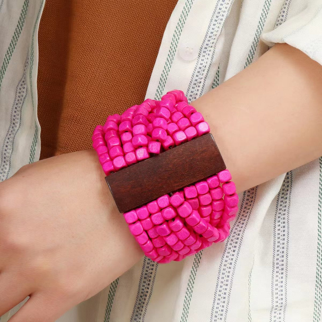 Bracelet femme en bois naturel rose vif à larges perles carrées et bande centrale en bois foncé.