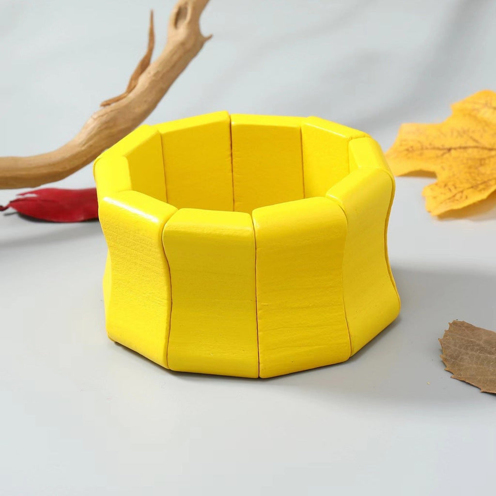 Bracelet large en bois naturel peint jaune solaire avec segments arrondis et finition lisse.