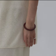 Jonc bracelet en bois marron foncé lisse porté au poignet femme, style naturel et élégant.