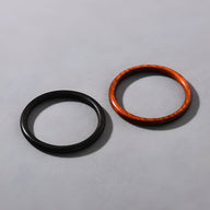 Deux bracelets joncs en bois, un noir mat et un marron avec veines naturelles, design épuré et élégant.
