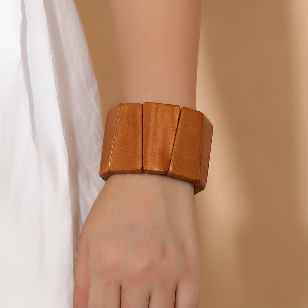 Bracelet manchette en bois naturel marron à larges panneaux sur poignet féminin.