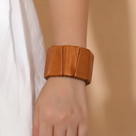 Bracelet manchette en bois naturel marron à larges panneaux sur poignet féminin.