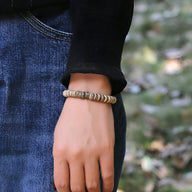 Bracelet mixte en coquilles de noix de coco marron naturel porté au poignet.