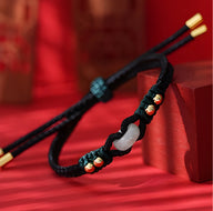 Bracelet en corde noire tressée avec pierre de jade blanche et perles dorées, style mixte.