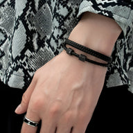 Bracelet en corde tressée noire, double tour avec fermoir mousqueton métallique noir, porté au poignet homme.