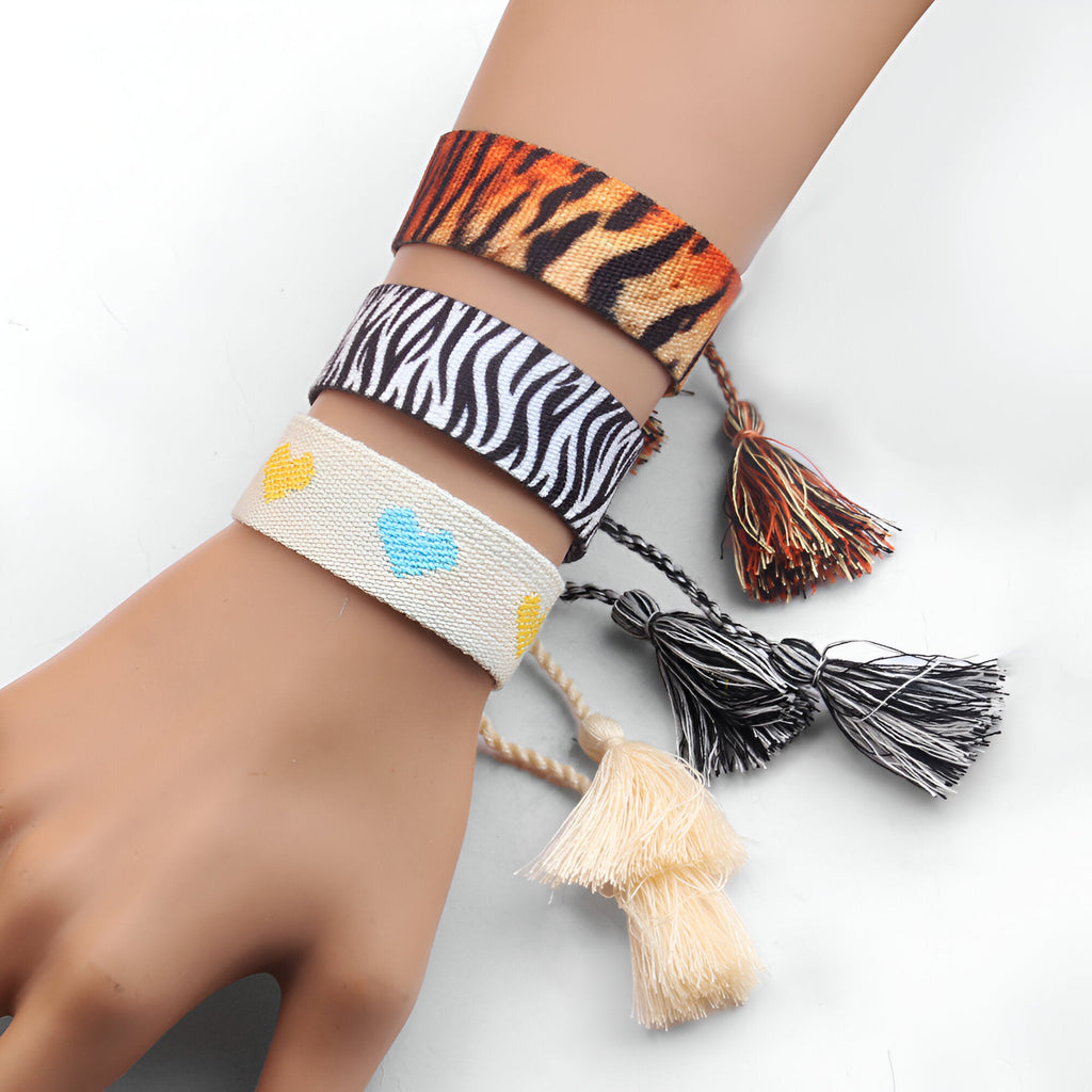 Bracelet en corde tressée à motifs tigre, zèbre et cœurs colorés avec pompons assortis.