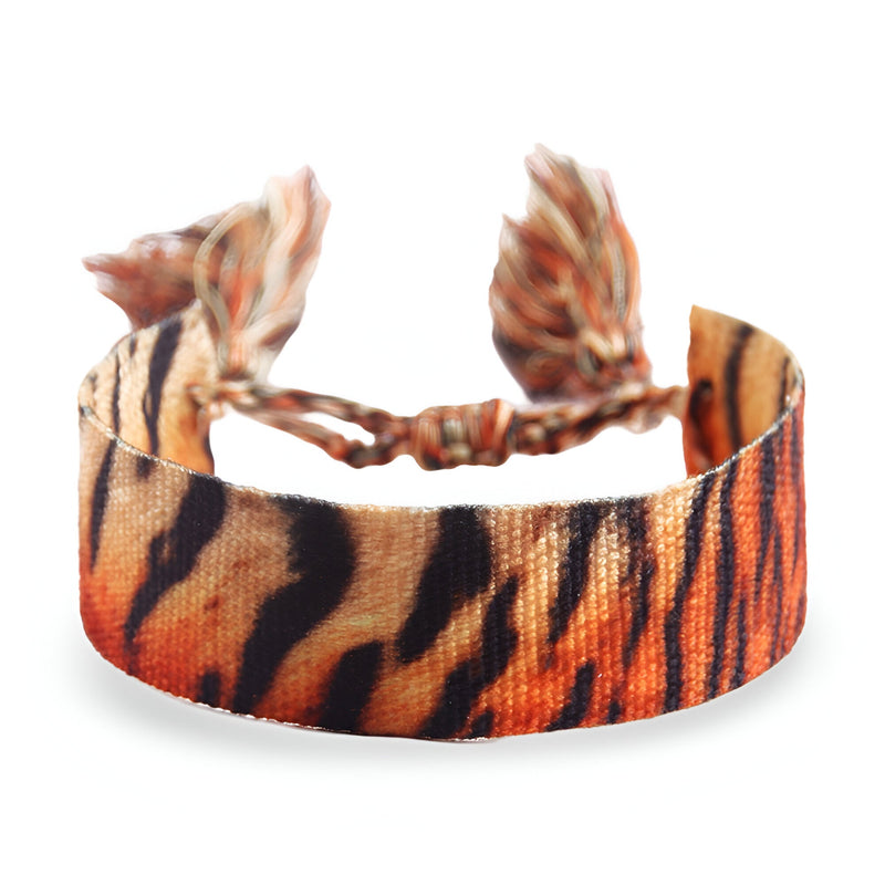 Bracelet en corde tressée à motif tigre orange et noir avec pompons réglables.