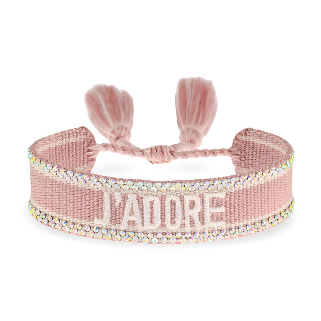 Bracelet tressé rose pâle avec inscription J'ADORE blanc et bordure strass brillante.