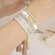 Bracelet en corde tressée beige et blanc avec inscription "J'adore" et "NATURE" en lettres dorées, style bohème.
