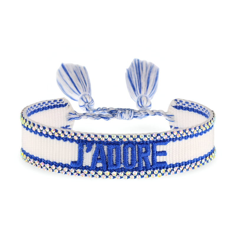 Bracelet en corde blanche et bleue tressée avec inscription "J'ADORE" en bleu et fermoir ajustable à pompons bleus.