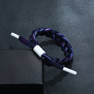 Bracelet en corde tressée bleu marine avec détails violets et fermoir blanc simple et coloré.