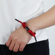 Bracelet en corde tressée rouge avec fermoir noir porté au poignet, style simple et coloré.