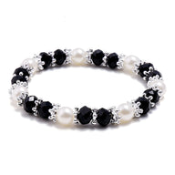 Bracelet élégant pour femme en perles noires facettées et perles blanches lisses, avec petits anneaux argentés entre les.