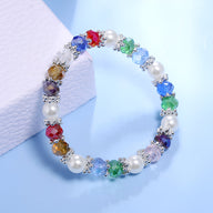 Bracelet multicolore avec perles blanches et cristaux taillés scintillants sur fil élastique.