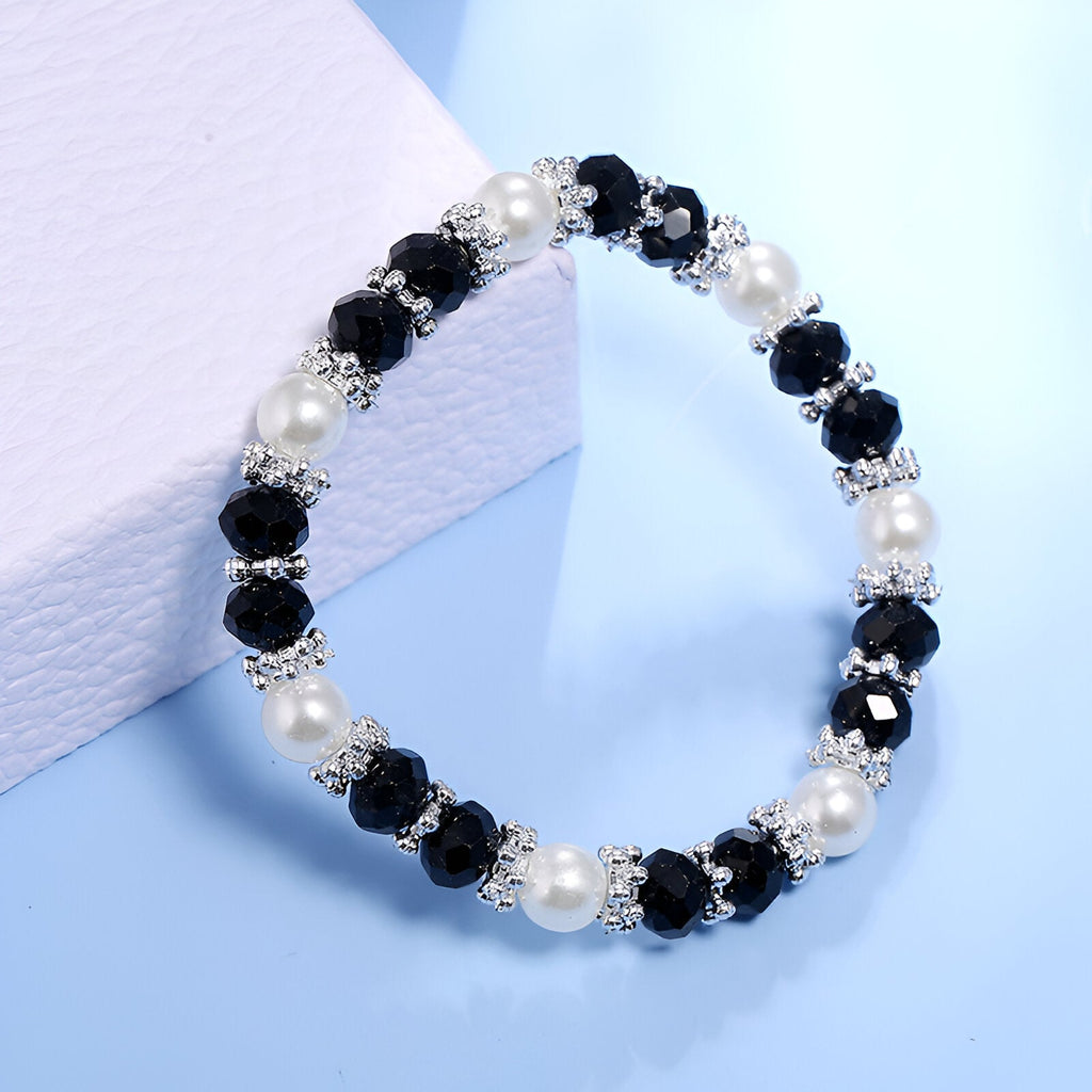 Bracelet femme perlé avec cristaux noirs, perles blanches et petits motifs argentés.
