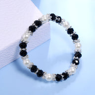 Bracelet femme perlé avec cristaux noirs, perles blanches et petits motifs argentés.