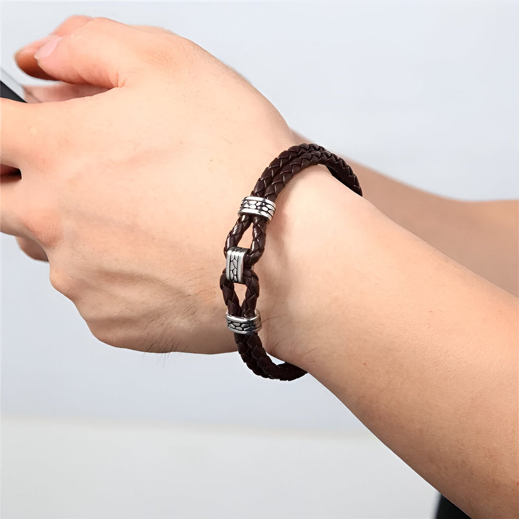 Bracelet homme en cuir tressé brun avec nœud et détails métalliques argentés.