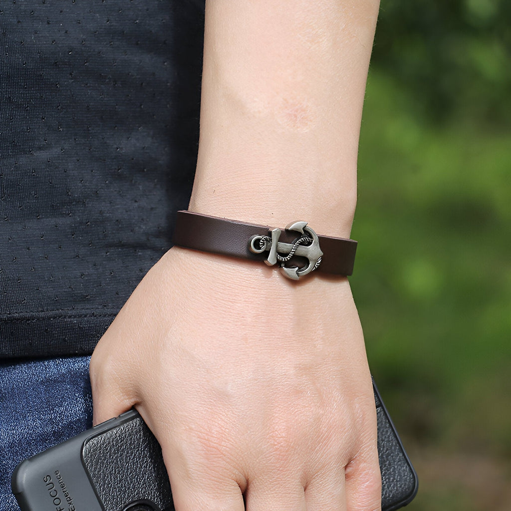 Bracelet en cuir marron avec ancre marine en métal gris comme fermoir, style masculin élégant.